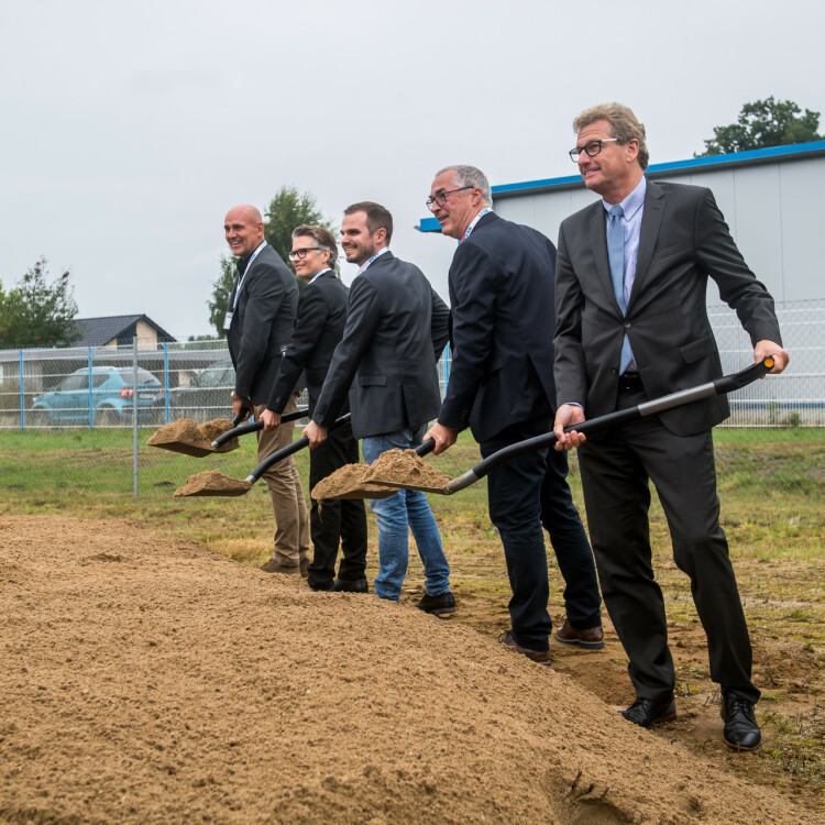 Fünf Männer haben jeweils eine Schaufel mit Sand in der Hand